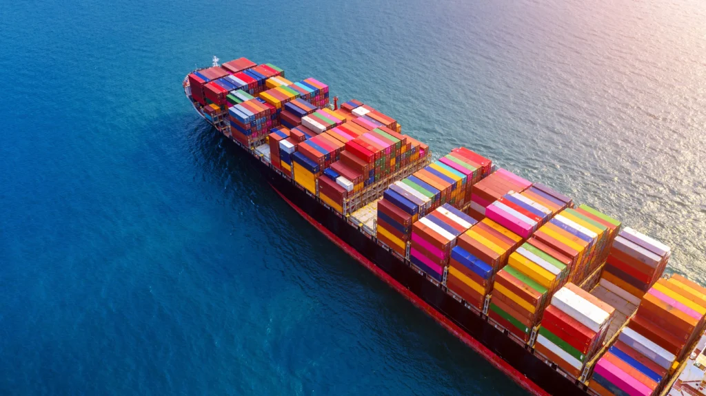 Sea freight cargo ship carrying shipping containers with port cranes loading bulk goods for international transport